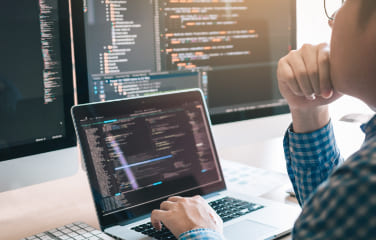 写真:PCとモニターを見る男性